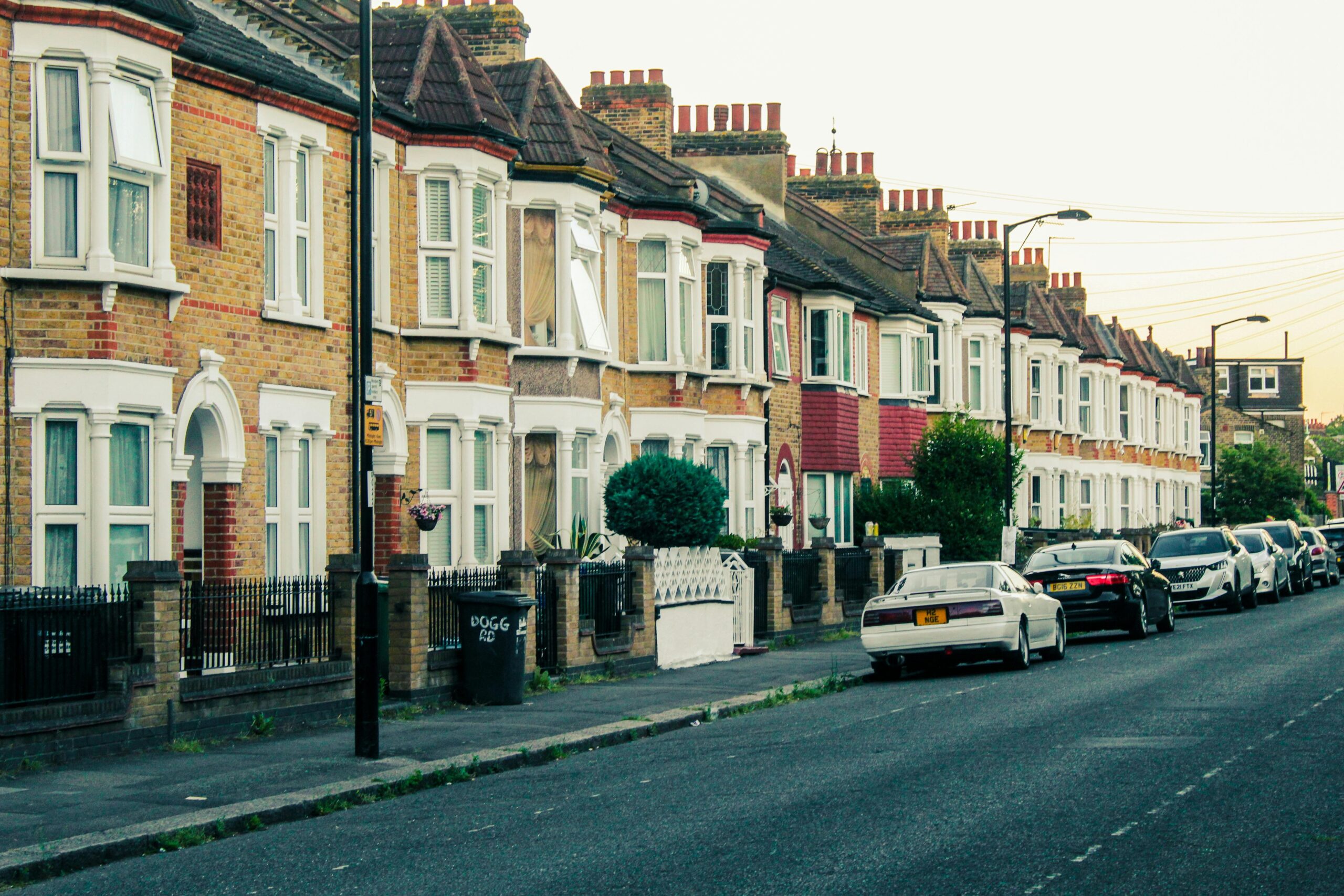 Charming view of traditional London terraced houses and parked cars along a quiet street at dusk.